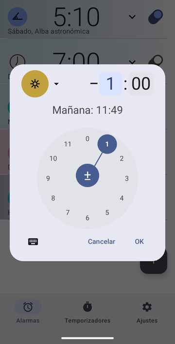 El cuadro de creación de alarma de Risetime, abierto sobre la lista de alarmas: el botón de ancla con el icono de Mediodía, un desplazamiento de menos 1 hora y 00 minutos con el campo de las horas seleccionado, y la línea Mañana: 11:49. Un disco de horas circular con el 1 seleccionado ocupa la mitad inferior, con Cancelar y OK debajo.